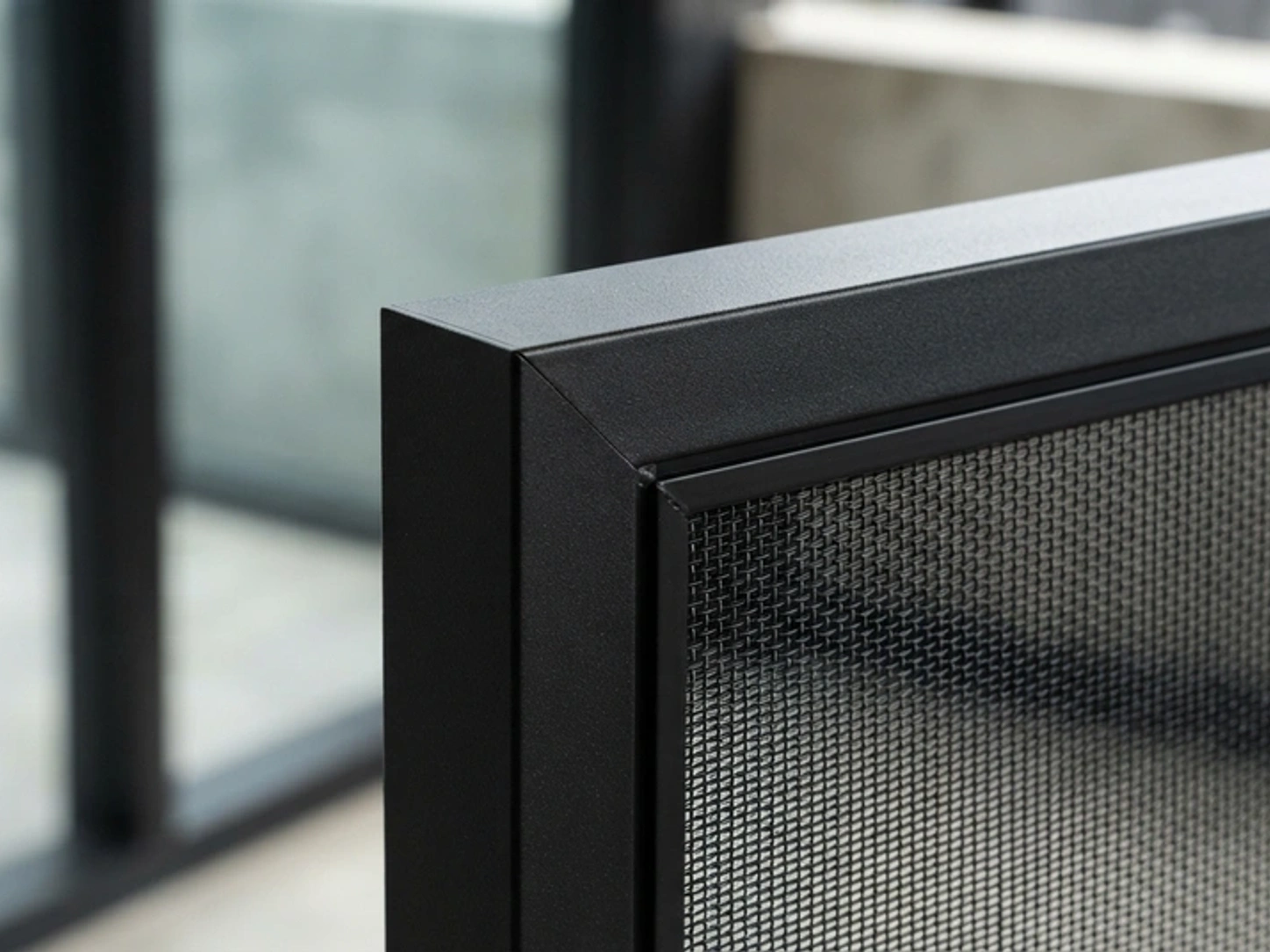 Minimalist architectural macro photography of a matte-black aluminium security screen frame showing clean mesh retention and precision corner joinery